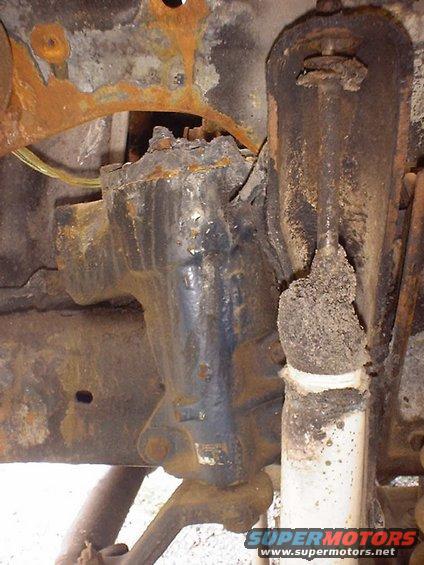 1988 Ford Bronco suspension part, heavily rusted, showing a black steering gear box and a white shock absorber