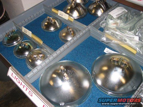 Automotive headlights organized in a gray storage tray with blue felt lining. Some headlights have labels