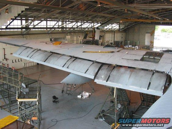 Airplane wing undergoing maintenance inside a hangar with scaffolding around it