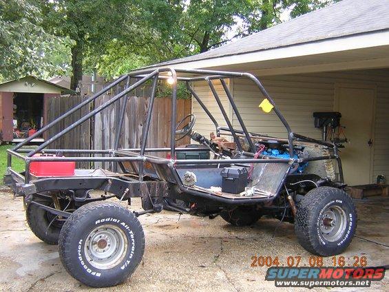 Custom buggy frame with roll cage, engine, and tires. It appears to be under construction