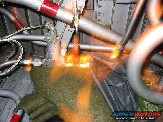 Aircraft interior with pipes, wires, and a green blanket