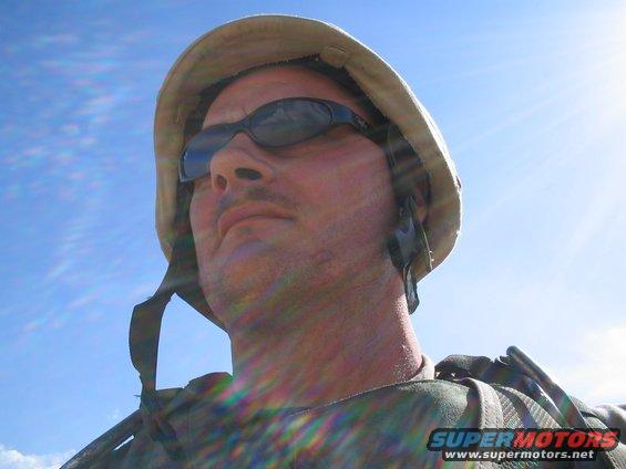 Soldier wearing helmet and sunglasses against a bright blue sky