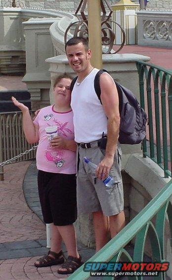 People posing at a theme park with a castle-like structure in the background