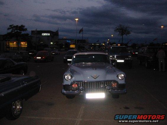 Light blue 1950s Cadillac parked at dusk, with other cars around