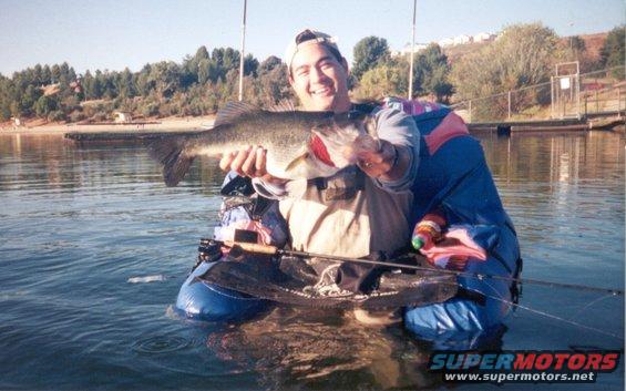 Guy in a float tube holding a big bass, lake in background