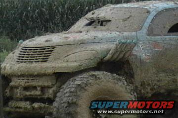 1989 Ford Bronco covered in mud, front grille and tire visible