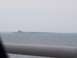 1990 Ford Bronco - A hazy view over water shows a distant structure, with a blurred foreground element.