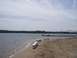 1990 Ford Bronco - A scenic view of a boat docked at a pier on a lake, with a sandy beach and benches in the foreground.