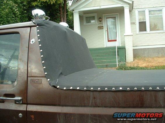Brown pickup truck side view with black tonneau cover and chrome spotlights on roof