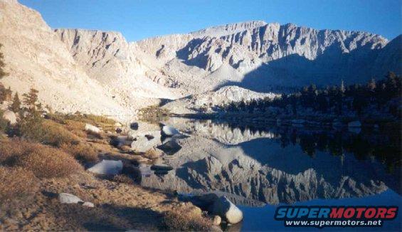 Mountain lake reflecting rocky peaks under a clear blue sky