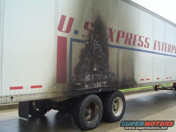 Side view of a U.S. Xpress trailer with significant burn marks and damage