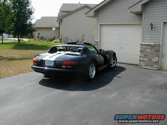 Black 1996 Dodge Viper with dual white racing stripes parked in a driveway next to a garage
