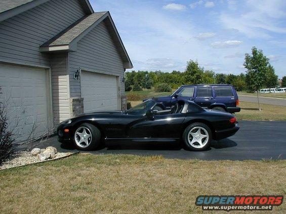 Black 1996 Dodge Viper convertible parked next to a garage, side view