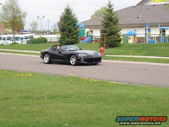 Black 1996 Dodge Viper convertible driving on a road, two people inside