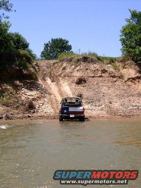 1978 Ford Bronco with Texas flag on rear driving through shallow water