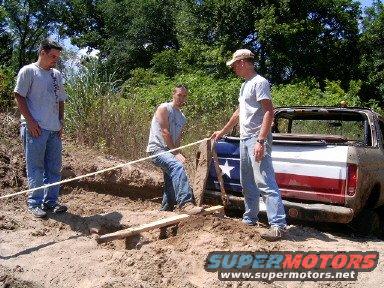 Rear view of a red, white, and blue vehicle being pulled from dirt