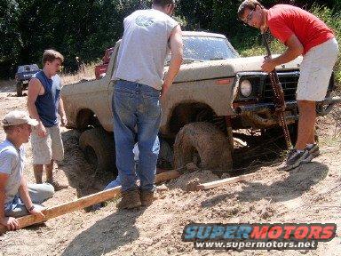 1978 Ford Bronco stuck in mud with people trying to free it