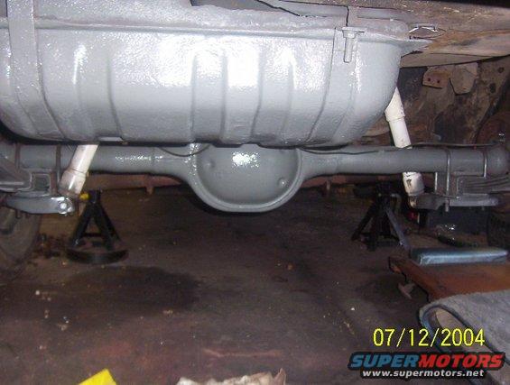 Gray painted rear axle and fuel tank assembly on jack stands