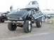 1994 Ford Bronco - Modified pickup truck with oversized tires and custom graphics on display at an outdoor event.