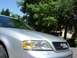 1999 Audi A6 - A silver 1999 Audi A6 is shown from the front-right, with trees and a house in the background.