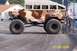 1979 Ford Bronco - A modified monster truck with camouflage paint and large tires is parked on a paved surface.