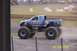 1979 Ford Bronco - A blue monster truck with "Broker" written on the side drives on a dirt track, kicking up dust.