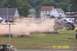 1979 Ford Bronco - Monster truck event with a truck jumping over destroyed cars in front of a crowd.