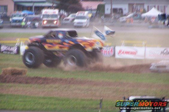 Monster truck with flame graphics driving on dirt track