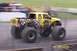 1979 Ford Bronco - A yellow monster truck with custom graphics drives on a dirt track.