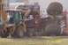 1979 Ford Bronco - A backhoe is used to lift a monster truck, which has extremely large tires, at an outdoor event.