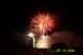 1979 Ford Bronco - A vibrant fireworks display lights up the night sky, with a streetlamp and buildings visible below.
