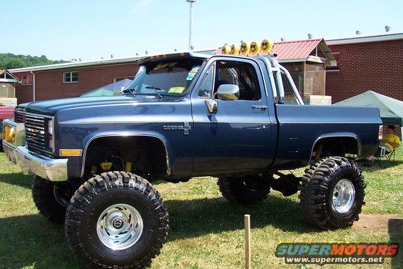 Blue lifted pickup truck with chrome grille and large off-road tires