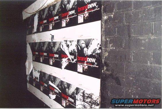 posters for 'brand new' plastered on a wall next to a brick surface