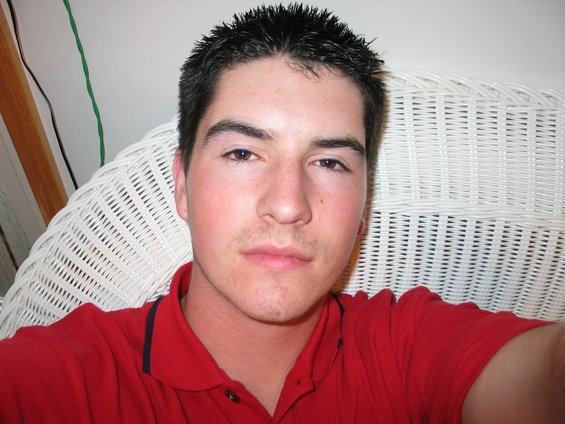 Man in red polo shirt sitting in white wicker chair