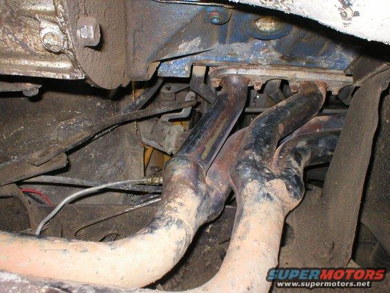 1978 Ford Bronco exhaust manifold, rusty and covered in dirt, viewed from below