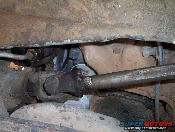 Underside view of vehicle showing driveshaft, U-joint, and oil filter. Supermotors.net logo visible