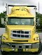 Yellow semi-truck front view, chrome bumper, grille, and headlights visible