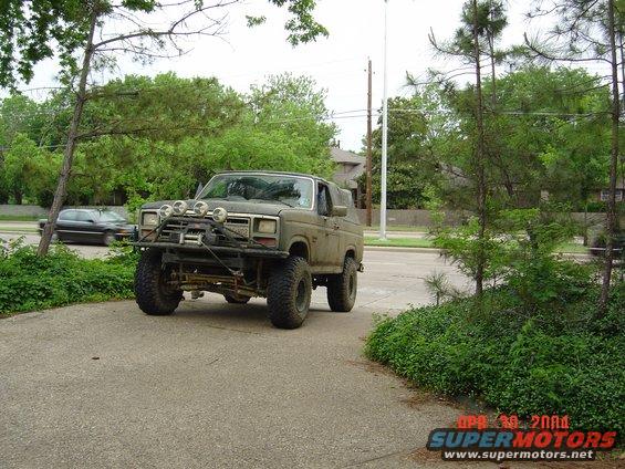 Olive green Ford Bronco with off-road lights and winch on front bumper parked on a driveway