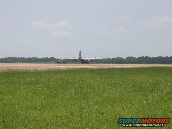 military cargo plane on runway with grass in foreground