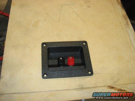 Speaker binding post with red and black terminals on a wooden surface
