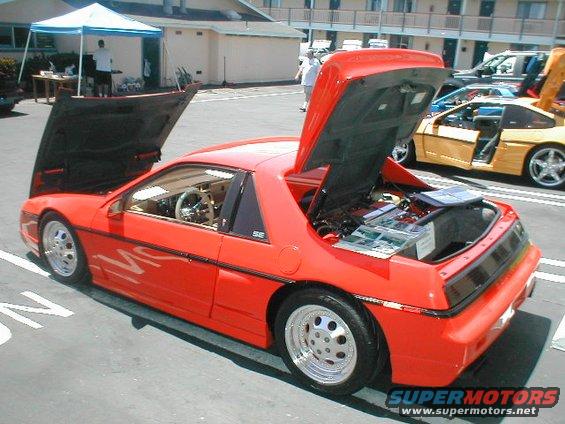 Red Pontiac Fiero with hoods open, showing engine and interior