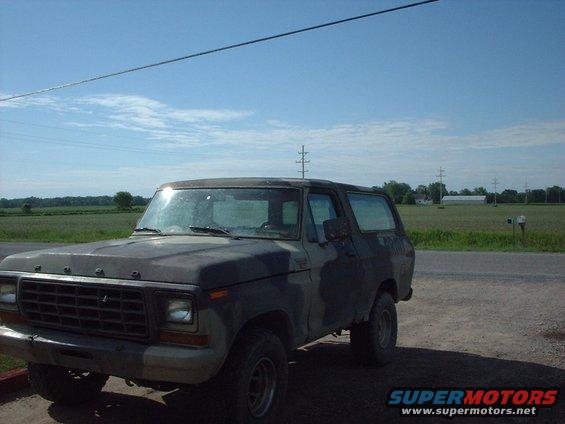 Ford Bronco with camouflage paint, parked on dirt road
