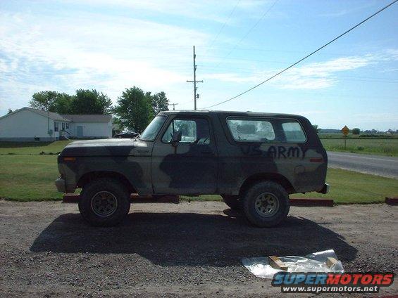 Camouflaged Ford Bronco with "US ARMY" text on the side, parked on a gravel lot