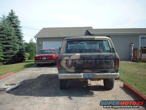 Rear view of a 1979 Ford Bronco with camouflage paint and graffiti, license plate YFZ 046