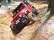 1984 Ford Bronco - A red Jeep Wrangler is stuck at an extreme angle in a deep dirt ditch during off-road driving.