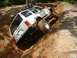 1984 Ford Bronco - A white Jeep Cherokee XJ navigates a steep, muddy incline during an off-road excursion.
