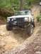1984 Ford Bronco - A white Jeep Cherokee XJ navigates a steep dirt trail during an off-road excursion.