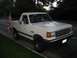 1988 Ford Bronco - This white Ford Bronco is parked curbside, displaying an American flag on its rear fender.