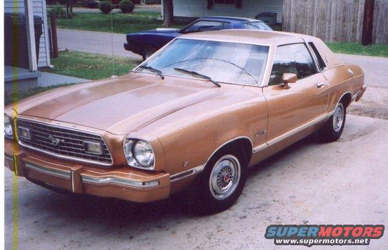 1978 Ford Mustang II coupe, tan color, parked on driveway. Blue car in background