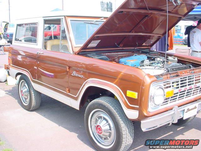 Brown Ford Bronco with hood open, showing engine. White roof and trim